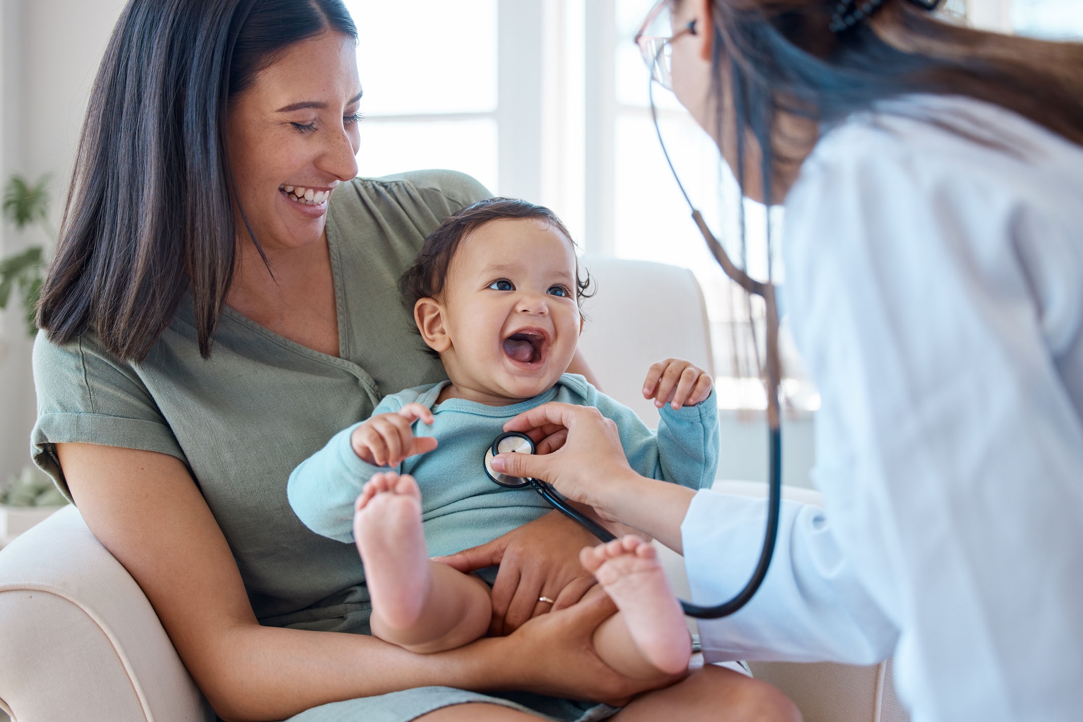 Mother holding smiling infant during a doctor's appointment