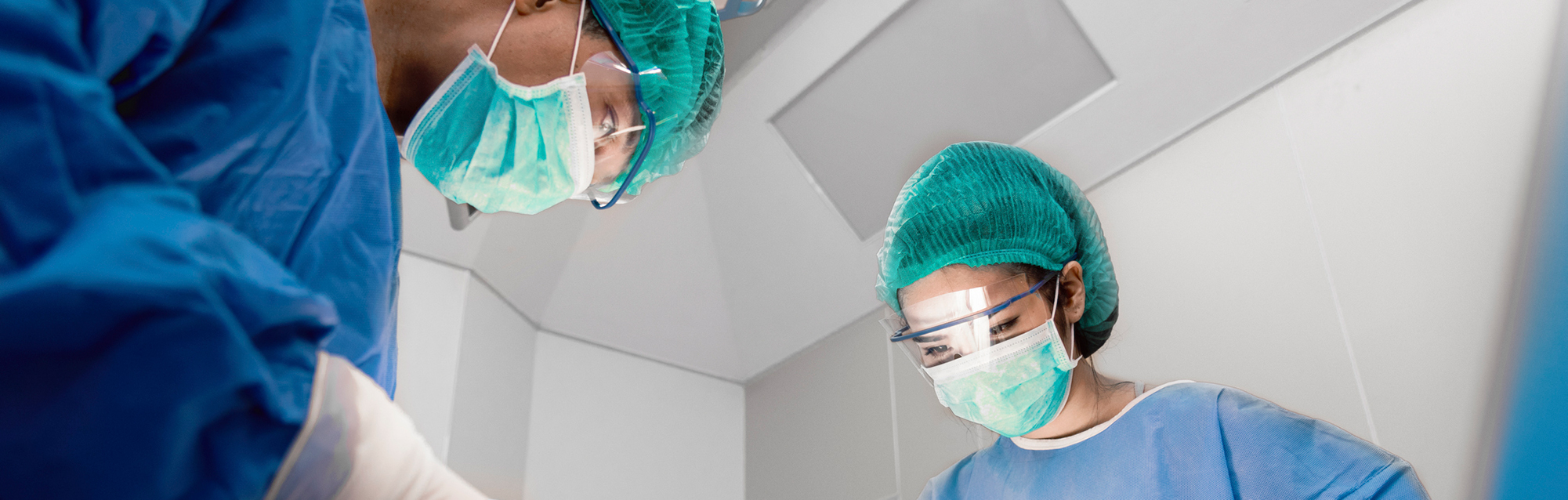 Close-up of surgeons wearing masks while performing a procedure in an operating room