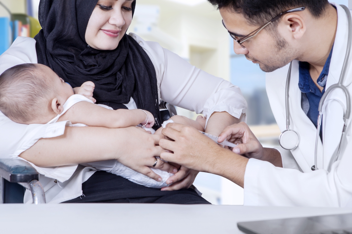 Male pediatrician doing vaccination to baby boy with a syringe in the hospital